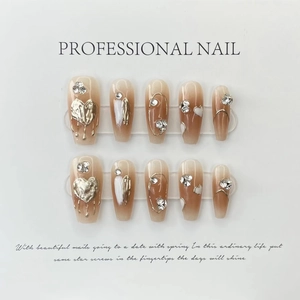 Detail van handgemaakte kunstnagels met gouden vloeibare metalen hartjes en kristallen