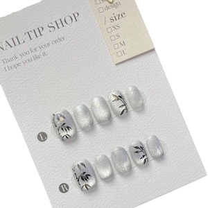 Bamboo style luxury press-on nails with silver cat-eye finish and black hand-painted leaves