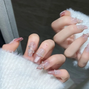 Handmade ballerina press-on nails with pink cat-eye finish, pearls, and gold ribbon art