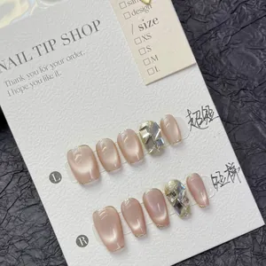Detail van handgemaakte nude roze cat-eye plaknagels in korte kistvorm met strassteentjes