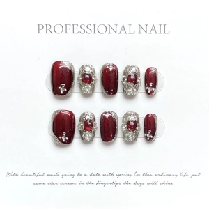 Detail of luxury handmade press-on nails in burgundy with pearls and rubies charms