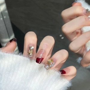 Faux ongles bordeaux et champagne avec paillettes, strass cœur et perles