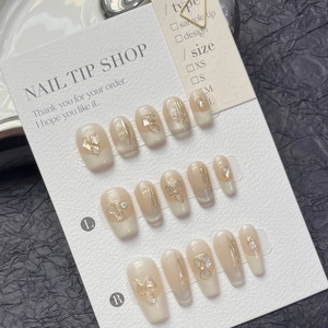 Close-up of handmade press-on nails featuring shell pieces and gold foil accents