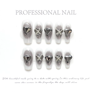 Detail of handmade press-on nails with 3D heart rhinestones and silver cross charms