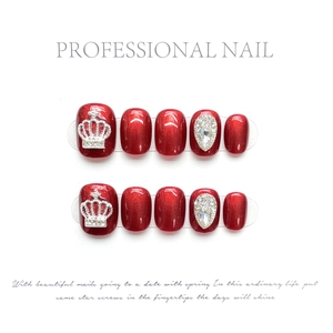 Detail of red cat-eye press-on nails with silver crown and teardrop rhinestone accents