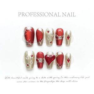 Detail of red press-on nails featuring heart-shaped rubies and gold embossed lines