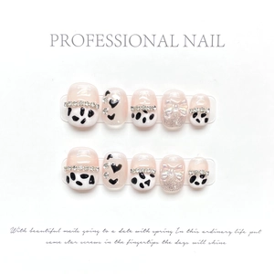 Detail of handmade press-on nails with cow print, 3D rhinestones and heart patterns