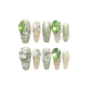 Handmade green glitter press-on nails with 3D rhinestones and butterfly decorations