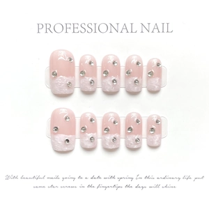 Detail of pink press-on nails with white fuzzy French tips and sparkling silver rhinestones
