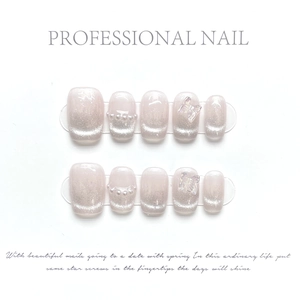 Macro detail of nude pink cat eye press-on nails with 3D butterflies and pearls