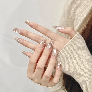 Detail of almond press-on nails with white floral patterns and 3D rhinestones