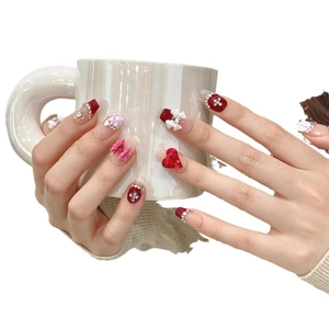 Handmade press-on nails with red bow, rhinestones and pink plaid design on model hands