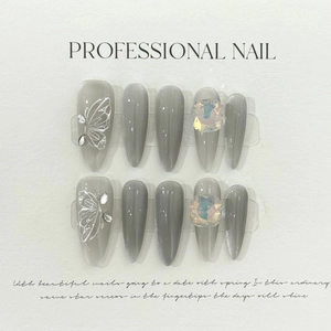 Détail de faux ongles amande avec finition œil de chat gris et motif ailes de papillon