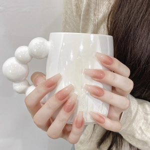 Elegant peach pink gradient long ballerina press-on nails shown on model holding a cup