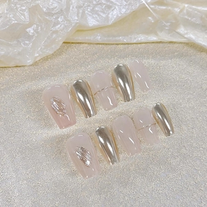 Détail de faux ongles cercueil longs avec relief doré 3D et finition rose nude