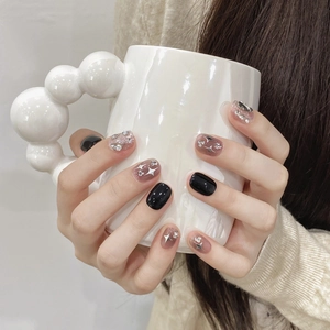 Short black sparkle press-on nails with silver star and rhinestone details on hands