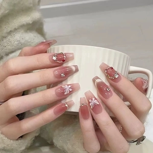 Detailed view of handmade pink gradient press-on nails with 3D white butterfly and gems