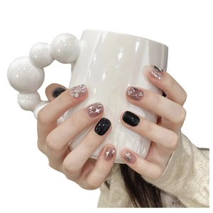 Handmade short press-on nails featuring black glitter, star motifs, and pink ombré rhinestones