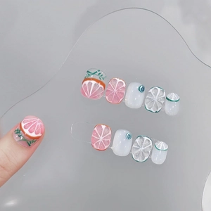 Handmade press-on nails with 3D citrus fruit motifs like grapefruit and lemon on clear tips