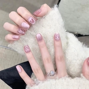 Detail of handmade pink cat-eye press-on nails with 3D heart embossed decorative accents