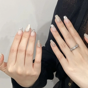 Long trapezoid press-on nails with nude pink gradient, rhinestones, and glitter accents