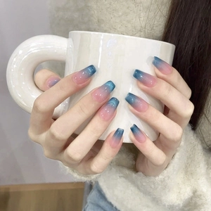 Blue and pink gradient press-on nails with silver glitter shown on model holding a cup