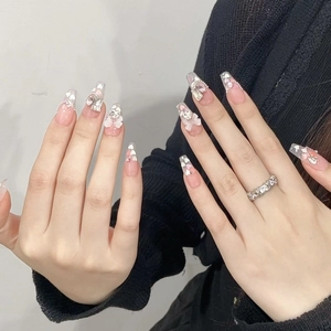 Handmade press-on nails with pink glitter hearts and white 3D bows in long coffin shape