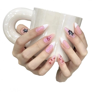 Pink cat eye press-on nails with black cartoon character and red bow designs