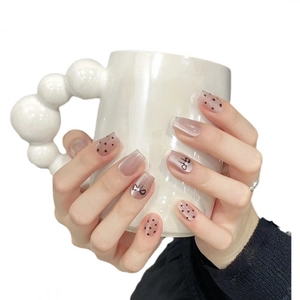 Pink and nude press-on nails with black bow knots, polka dots and pearl accents