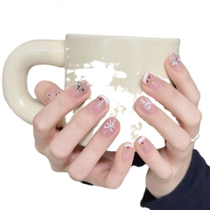 Hand-painted cherry press-on nails with white bows and sparkling rhinestones