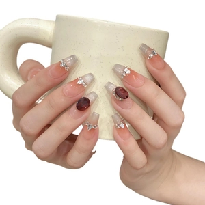 Long square press-on nails with pink gradient and luxury rhinestone gems on a ceramic cup