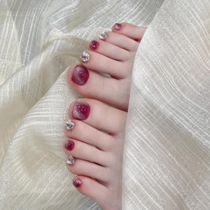 Handmade burgundy cat eye press-on toenails with silver glitter on silk background