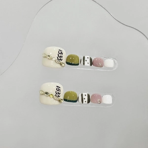 Handmade emerald green press-on toe nails with metallic chain and rhinestone accents