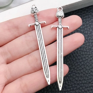 Detailed close-up of silver alloy sword pendants featuring wolf head and textured hilts