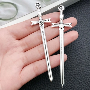 Macro detail of antique silver sword pendants with celtic cross engraving on hand