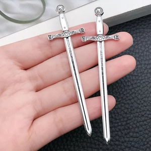 Detailed close-up of antique silver sword charms for DIY jewelry and bookmark making