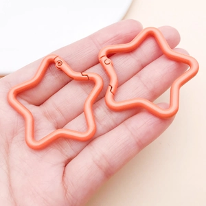 Matte coral orange star-shaped aluminum alloy carabiners for DIY keychains held in hand