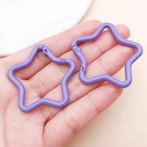 Close-up of two light purple star-shaped carabiners held in palm for size comparison