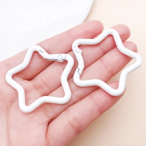White star-shaped spring buckles held in hand to demonstrate size for DIY keychain crafts