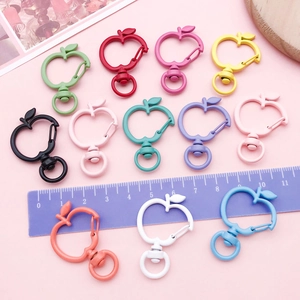 Colorful apple-shaped zinc alloy lobster clasps with rotating rings on pink background
