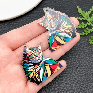 Close-up of colorful geometric acrylic cat charms held in hand for size reference