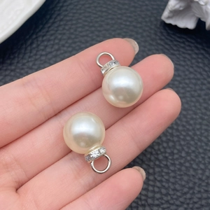 Dettaglio di ciondoli con perle ABS e ganci in argento con strass tenuti in mano