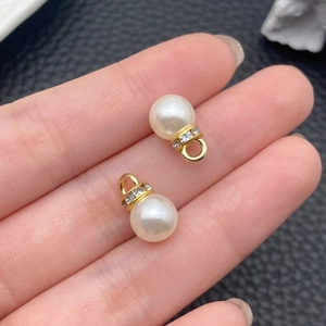 Vista macro di due perle ABS bianco crema con anelli di strass dorati per gioielli fai-da-te