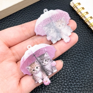 Detalle del colgante de acrílico con dos gatitos bajo un paraguas rosa para bricolaje