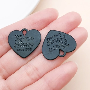 Détail macro de pendentifs coeur en métal noir avec gravure 'Mozto Hiano since 1988'
