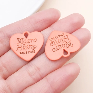 Gros plan de pendentifs cœur orange corail avec texte gravé pour création de bijoux