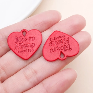 Vue détaillée de deux pendentifs en forme de cœur rouge avec texte en relief et œillet