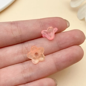 Close-up of frosted acrylic trumpet flower beads held on fingertips for DIY jewelry making