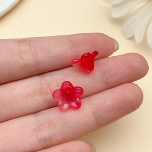 Macro shot of two small red acrylic trumpet flower beads for DIY jewelry making