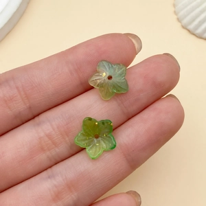 Primer plano de cuentas de pétalos verdes con pan de oro para creación de joyería DIY